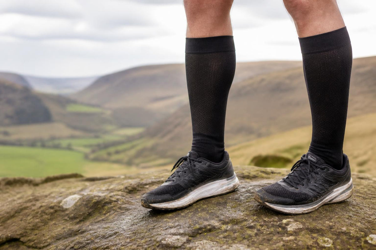 A pair of athletic compression socks pulled taut over a runner’s lower legs against a neutral background