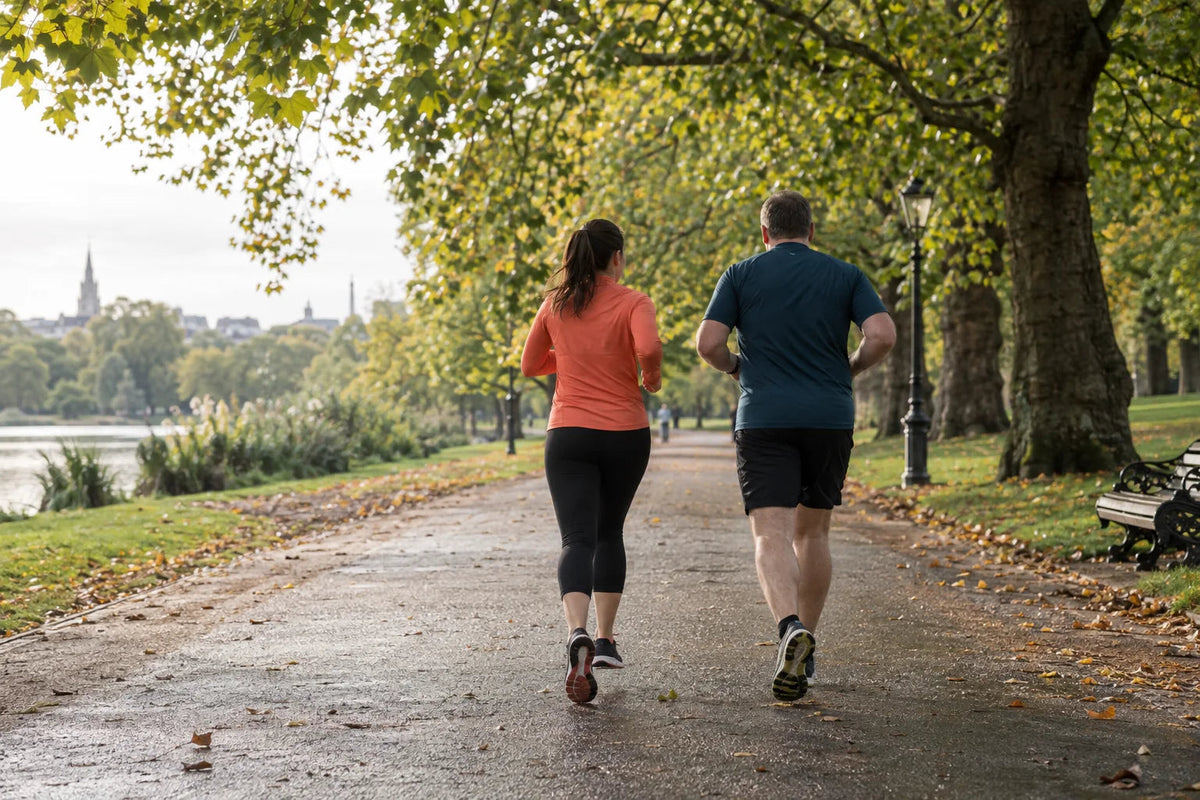 Two recreational runners jogging together along a tree-lined park path